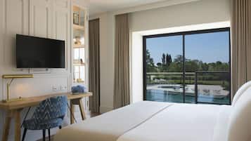 Une chambre d’hôtel avec un grand lit, un bureau avec une télévision, une chaise et une vue sur une piscine.