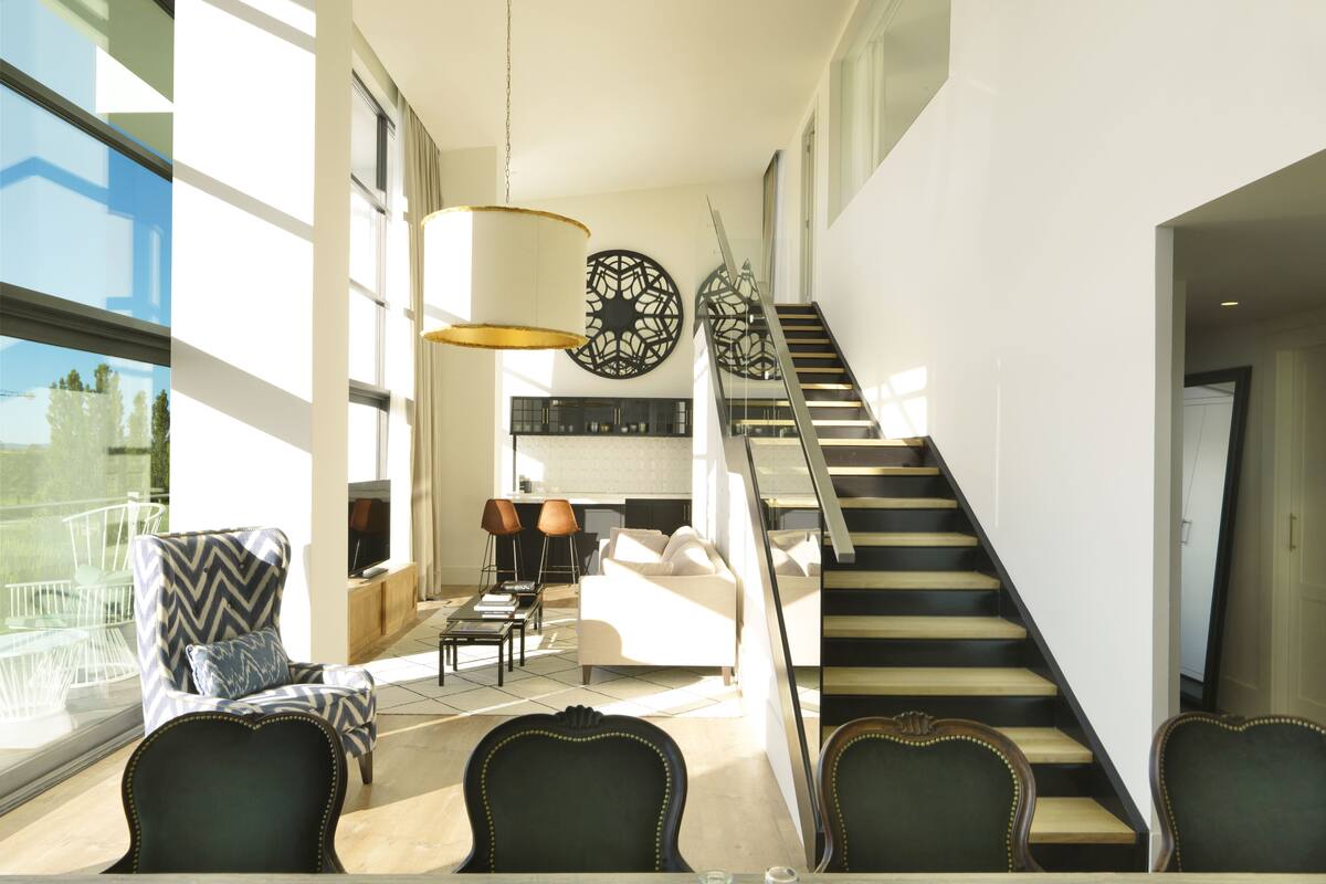 Un vaste espace de vie comprenant une table à manger, des chaises et un escalier menant à l’étage supérieur.