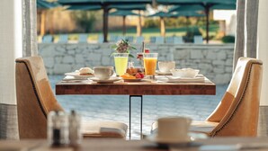 A dining table with breakfast items, a view of a pool and umbrellas outside. - Hotel Camiral - The Leading Hotels of the World (Caldes de Malavella)