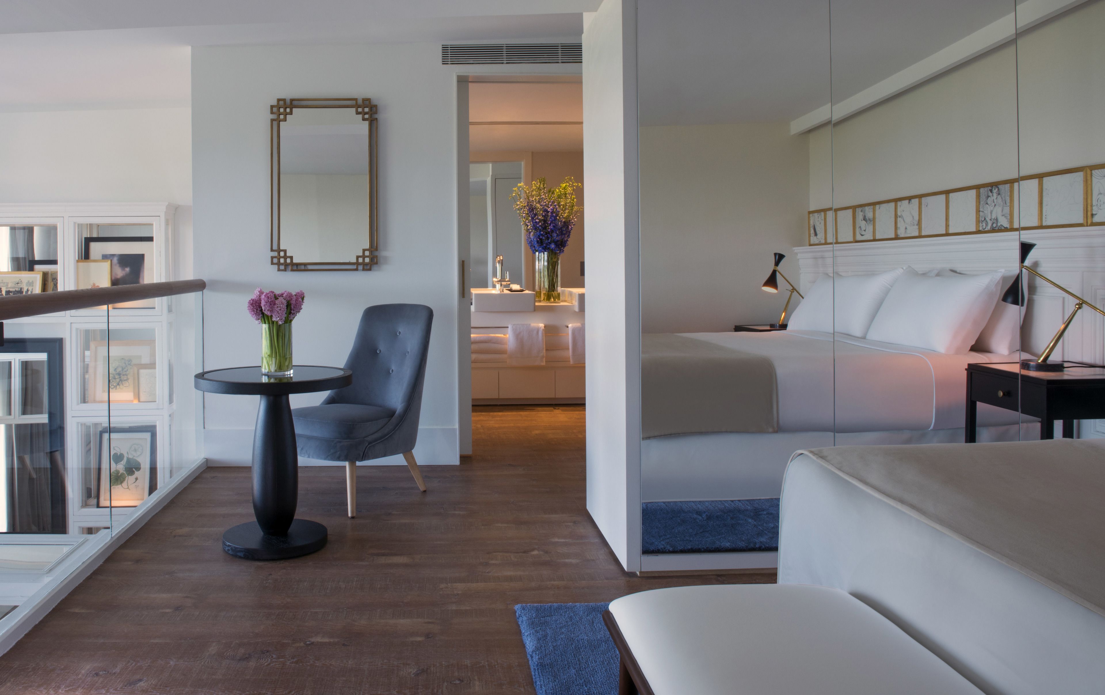 Una habitación de hotel con cama, una silla, una mesa y un espejo.