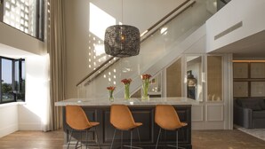 A modern kitchen with a large island, three bar stools, and a hanging light fixture. - Hotel Camiral - The Leading Hotels of the World (Caldes de Malavella)