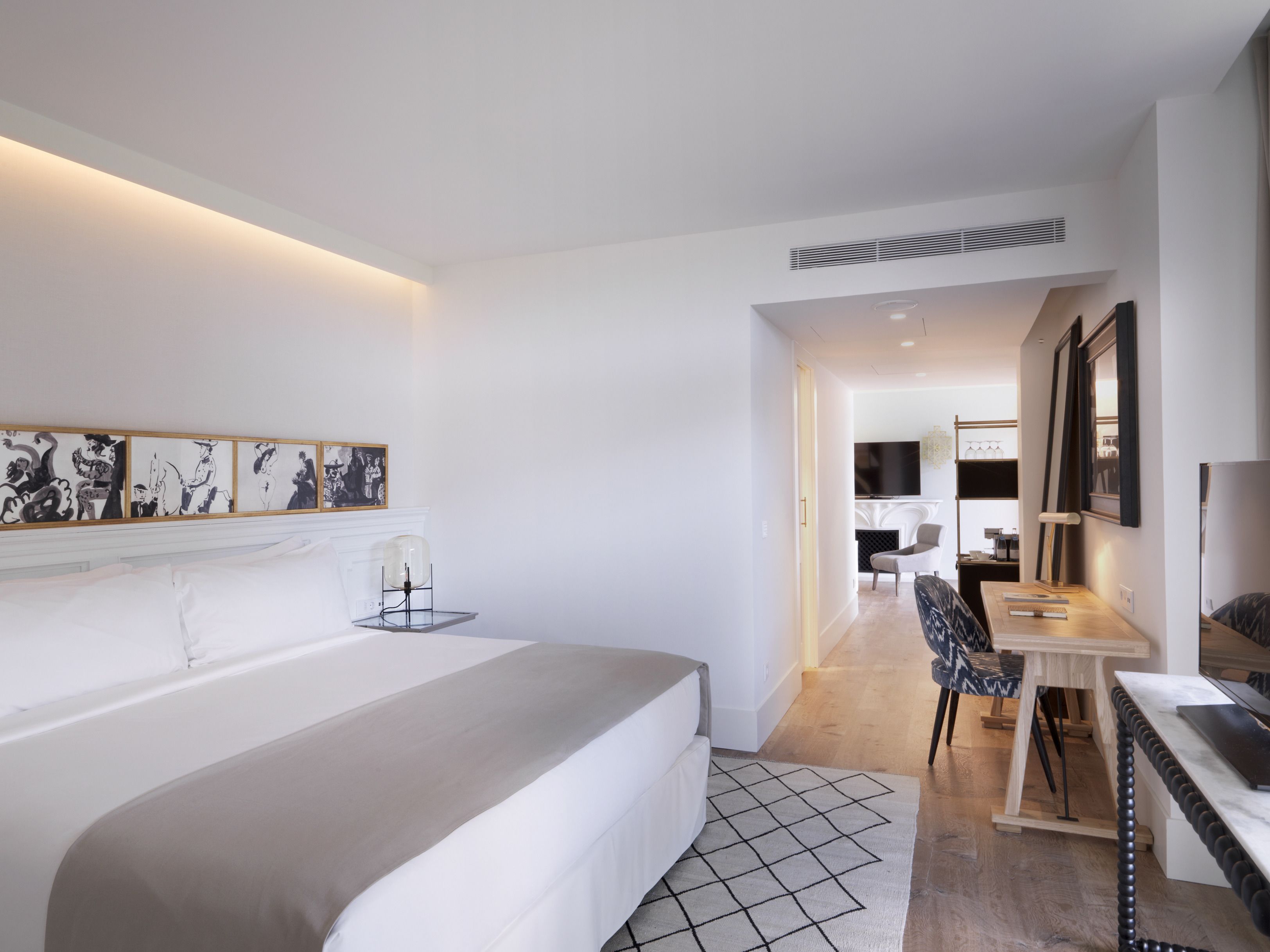 A modern bedroom with a large bed, a desk, and a chair.