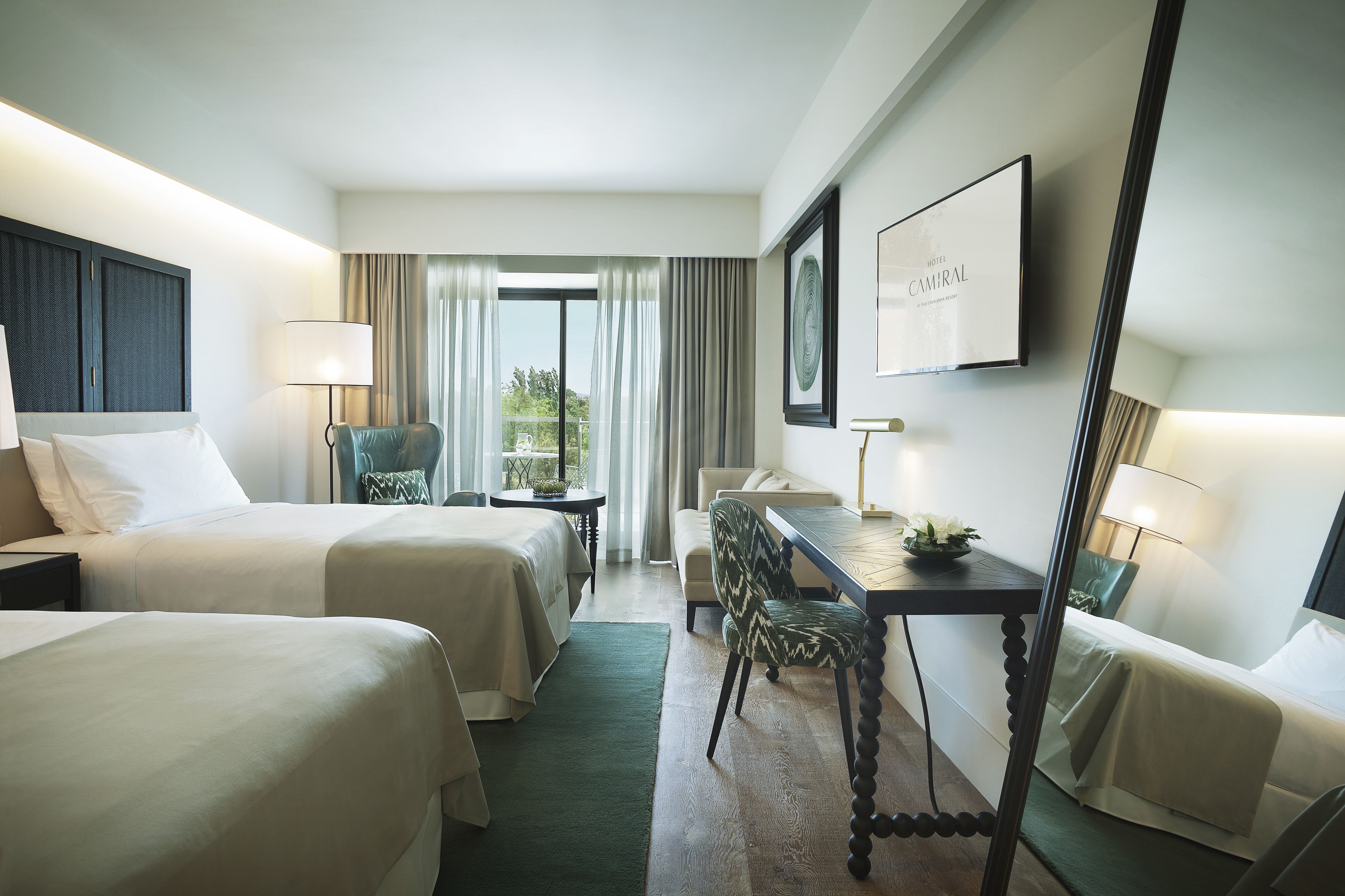 Habitación de hotel con dos camas, una mesa de comedor, una silla y vistas al exterior.