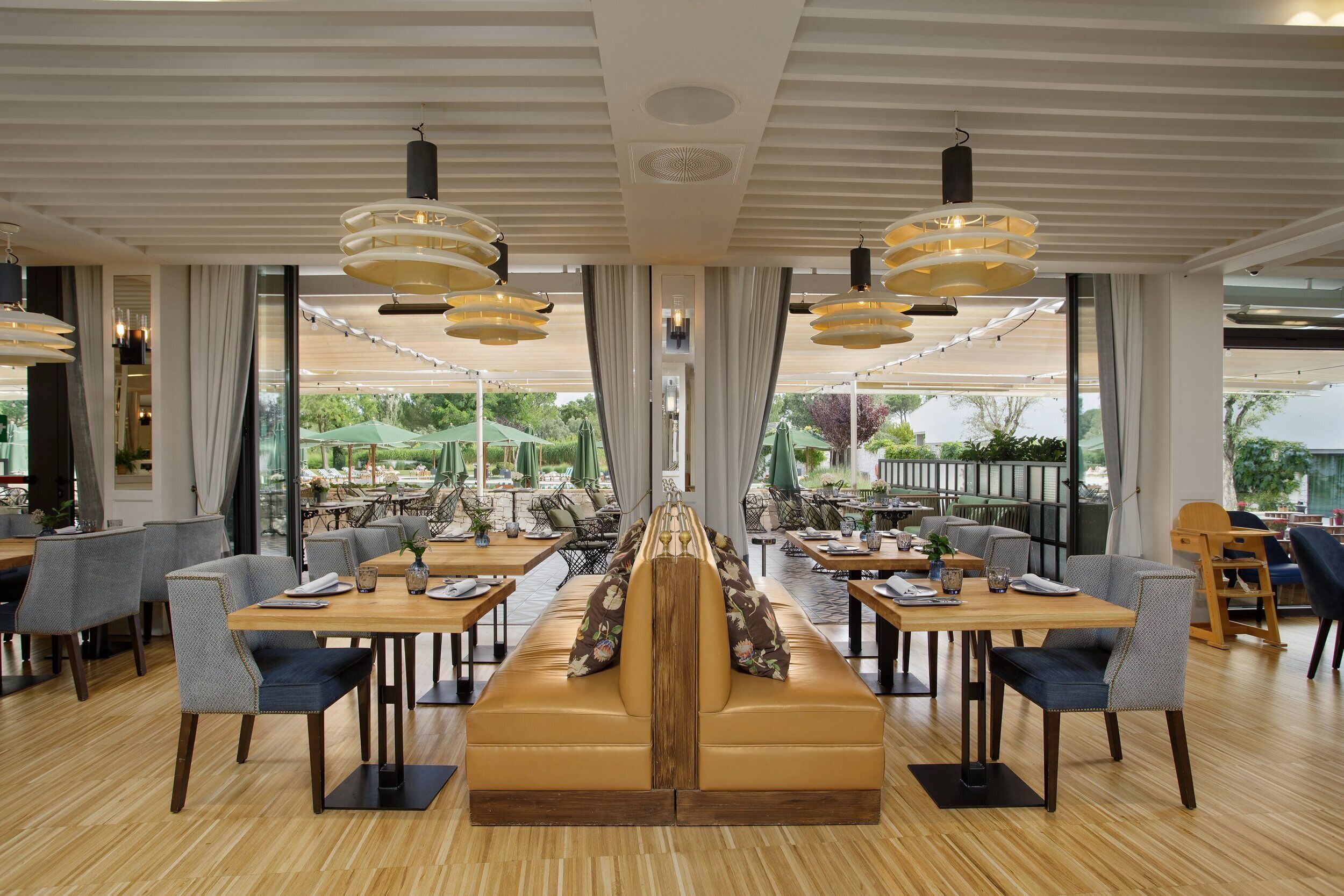 Un restaurant doté d’un espace central avec des sièges, de nombreuses tables et des luminaires suspendus.