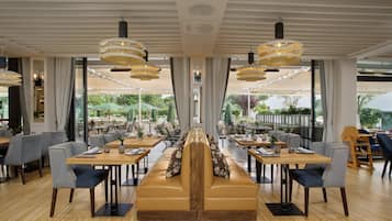 Un restaurant doté d’un espace central avec des sièges, de nombreuses tables et des luminaires suspendus.