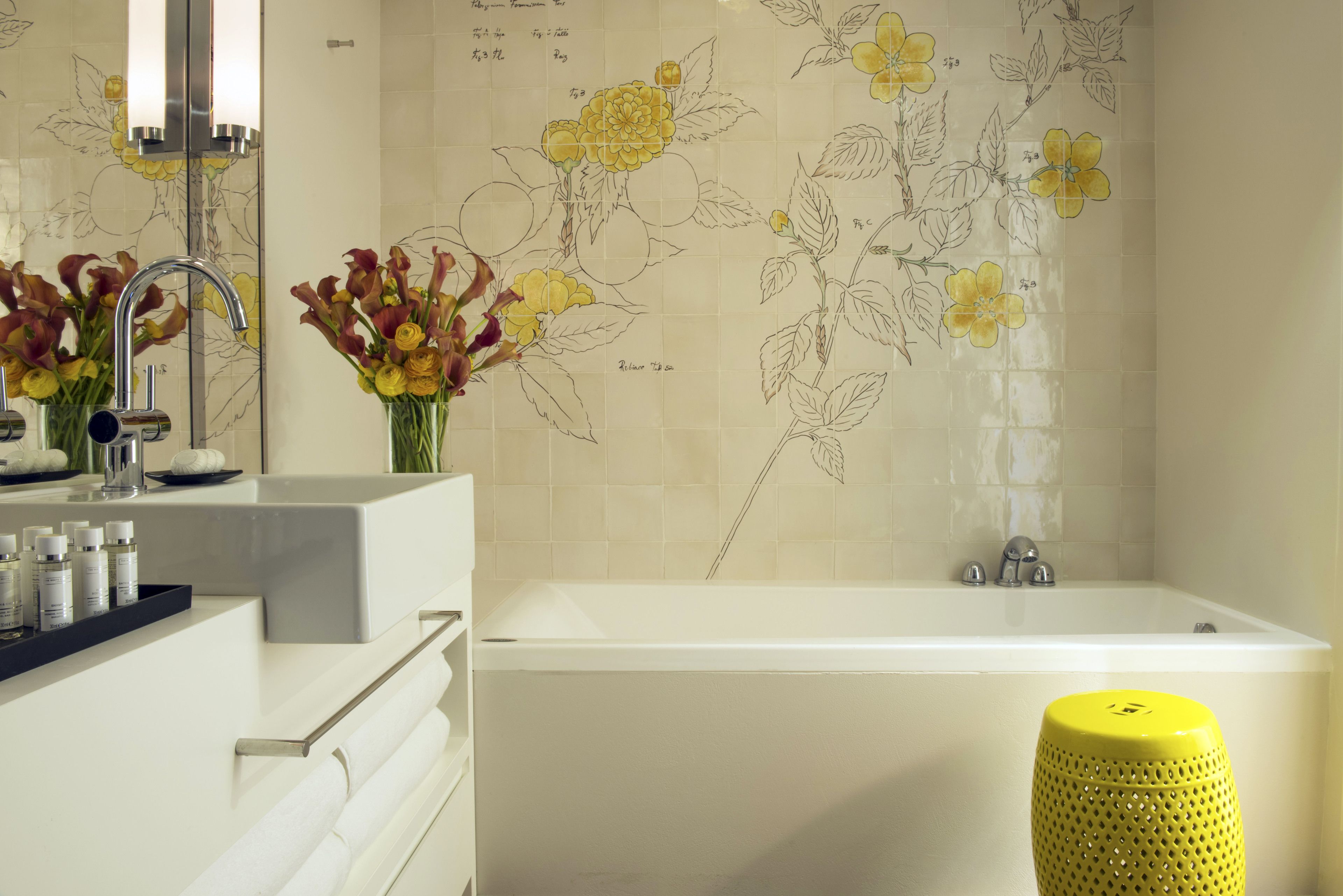 A modern bathroom with a bathtub, a vanity with a mirror, and a yellow stool.