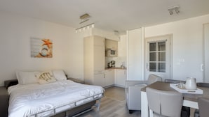 A modern hotel room with a bed, a dining area, a kitchenette, and a bathroom. - Evancy Etoile des Dunes (Bray-Dunes)