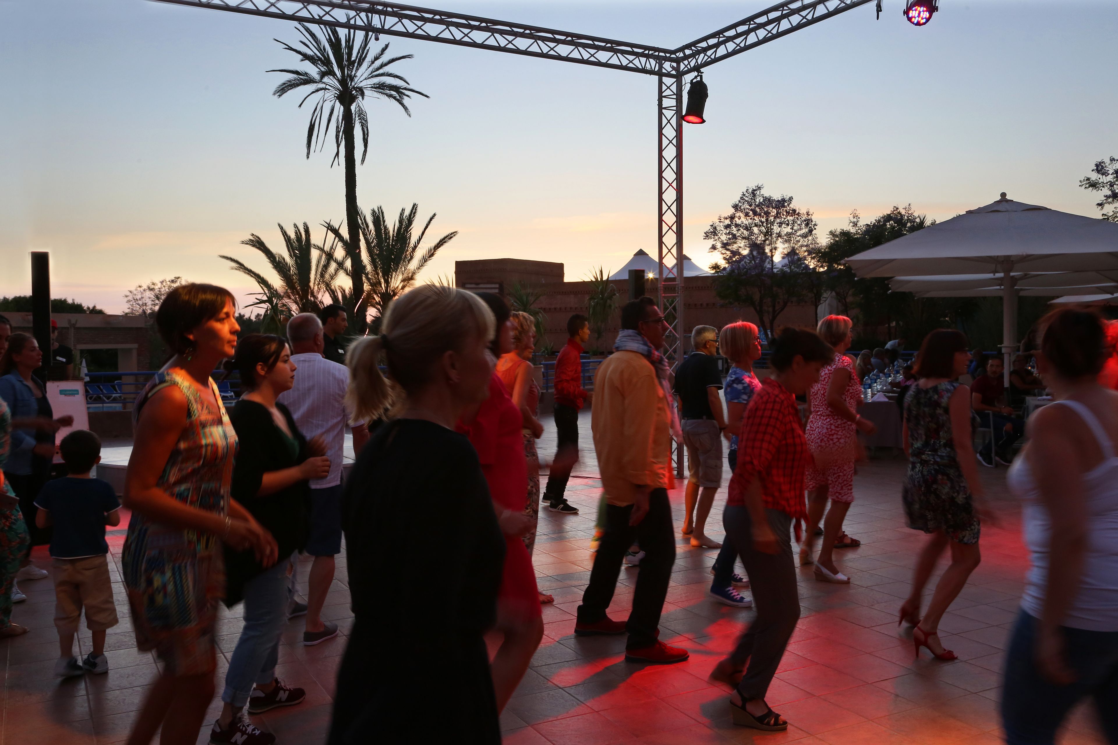 A crowded outdoor area with a stage and a large umbrella.