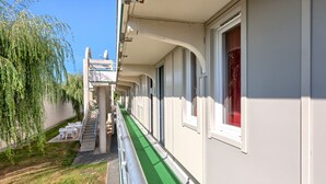 A corridor with a green pathway, white walls, and windows with red curtains. - Première Classe La Roche Sur Yon - Vendéspace (Mouilleron-le-Captif)