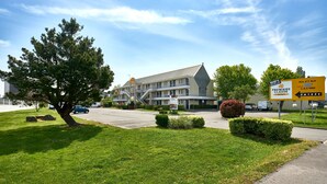 A hotel with a large parking lot, a tree, and a sign indicating WiFi availability. - Première Classe La Roche Sur Yon - Vendéspace (Mouilleron-le-Captif)