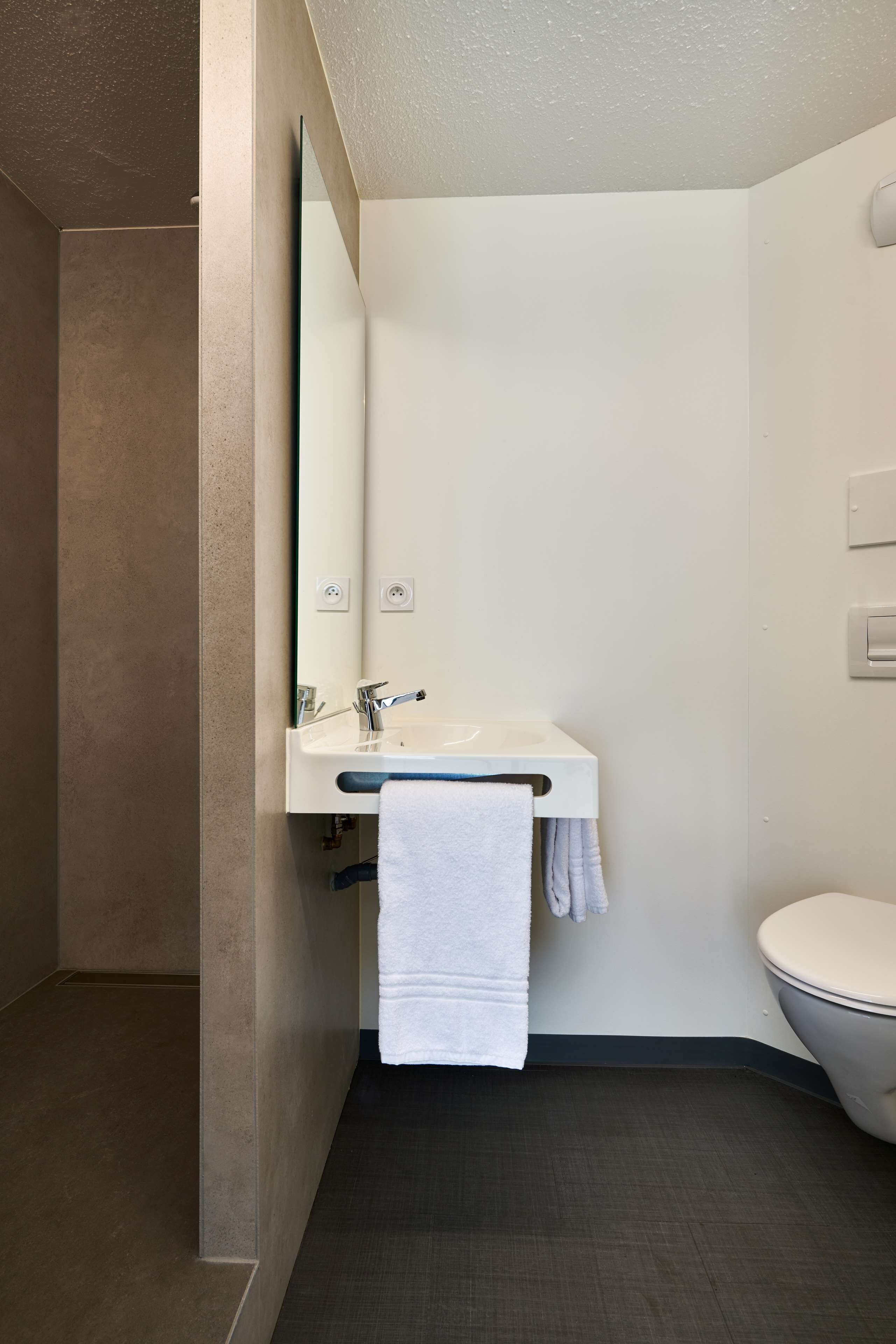 Ein modernes Badezimmer mit Waschbecken, Spiegel und Toilette.