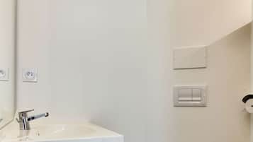 Un baño pequeño y moderno con un lavamanos blanco, una toalla colgada en la pared, un inodoro y un interruptor de luz.