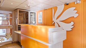 A reception area with a modern design, featuring a counter and a decorative leaf motif on the wall. - Première Classe La Roche Sur Yon - Vendéspace (Mouilleron-le-Captif)