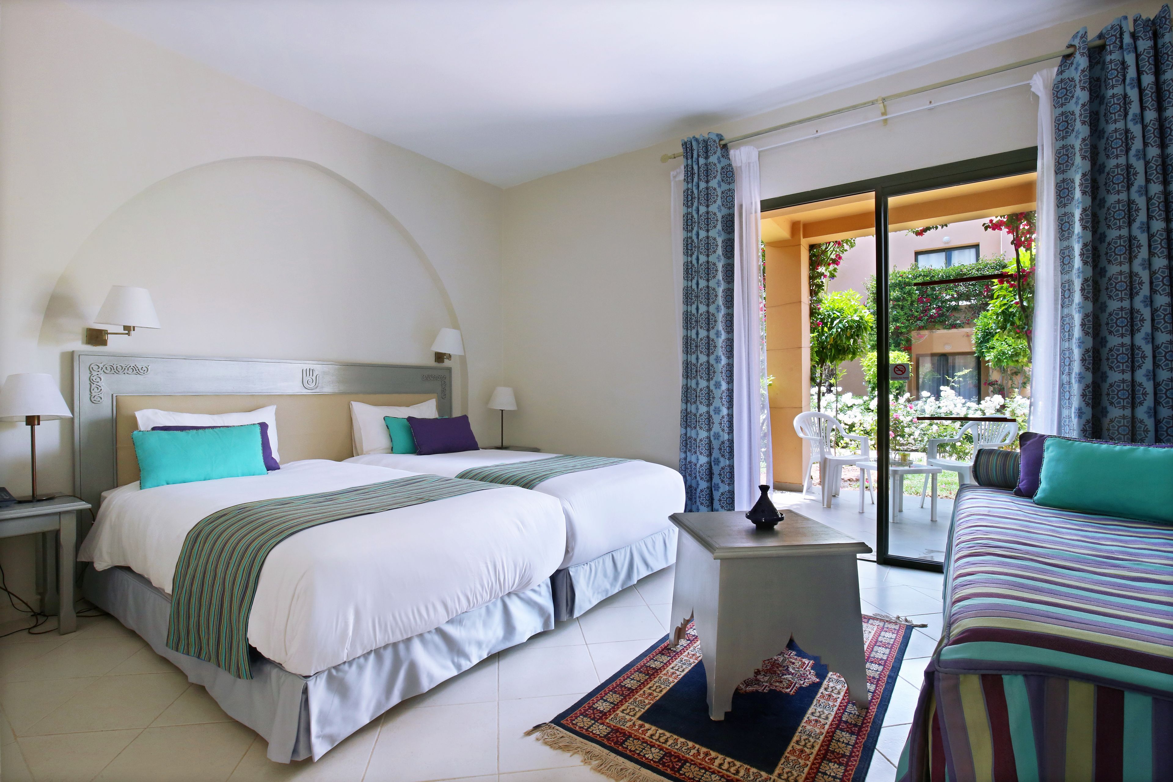 Habitación de hotel con una cama grande, un escritorio pequeño y vistas al balcón exterior.