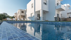 Un edificio moderno con piscina, fachada blanca y varios balcones.