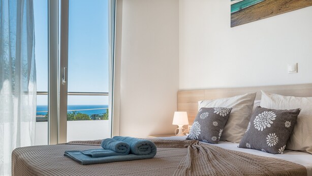 Un cuarto de hotel con una cama, vista al mar y un cuadro en la pared.