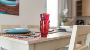 Una mesa de comedor con copas rojas, platos azules y un posavasos tejido.