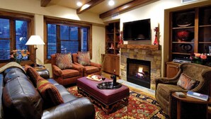 A cozy living room with a fireplace, leather sofas, a flat-screen TV, and a bookshelf. - The Innsbruck Aspen by Frias (Aspen)