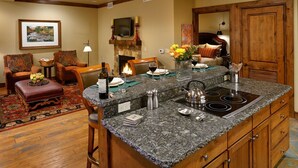 A spacious living room with a fireplace, a dining area with a granite island, and a cozy seating area with patterned chairs. - The Innsbruck Aspen by Frias (Aspen)