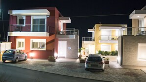 Edifici residencial modern amb múltiples balcons, un cotxe davant i plantes en testos.