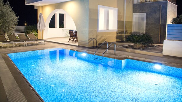 Una piscina amb una casa moderna al fons.
