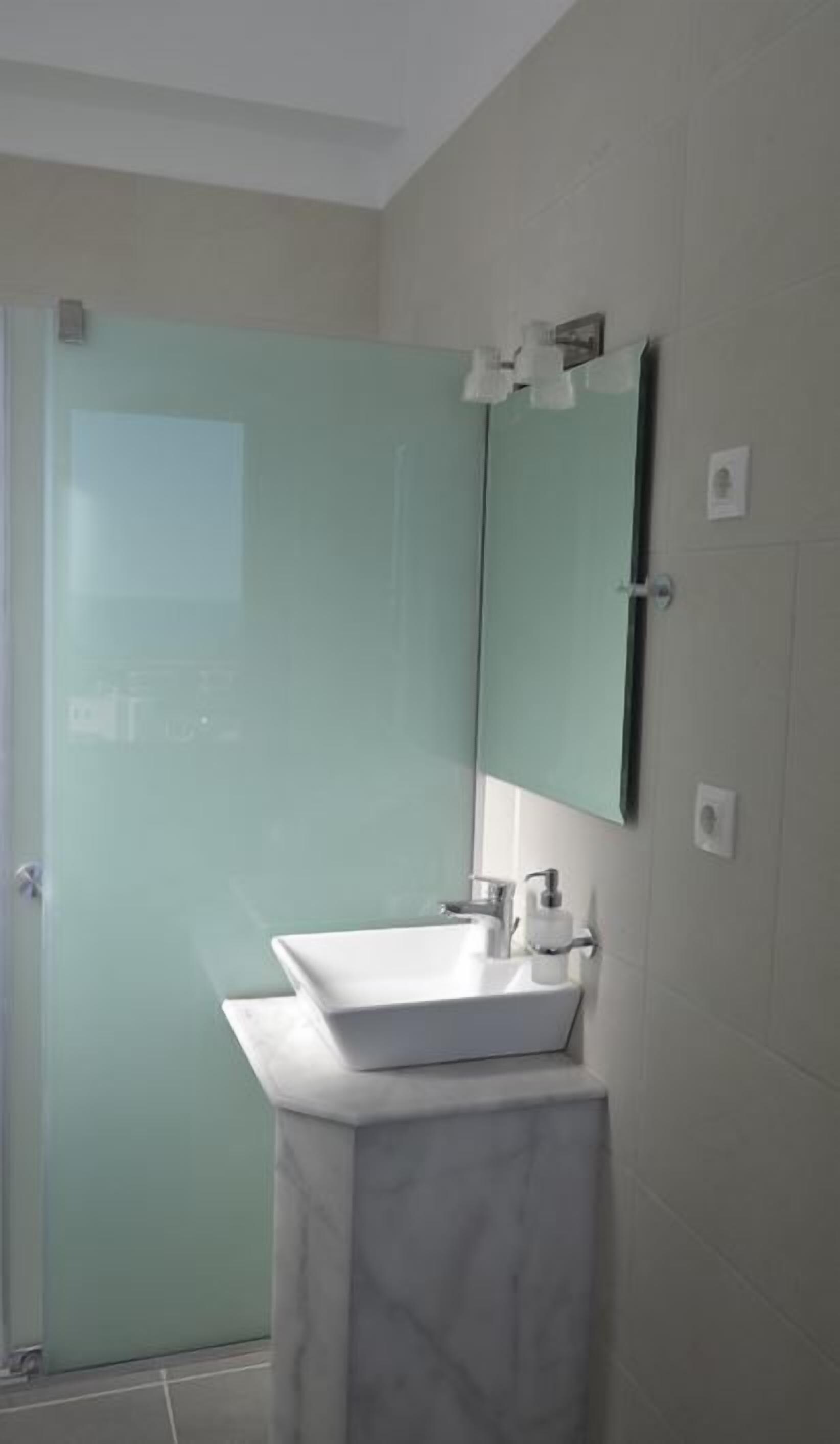 A bathroom with a white sink, a mirror, and a glass shower enclosure.