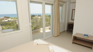 Habitació d'hotel amb un llit, una taula petita, una cadira i vista al mar i edificis.