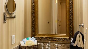 A bathroom with a large mirror, a sink, and a vanity area.