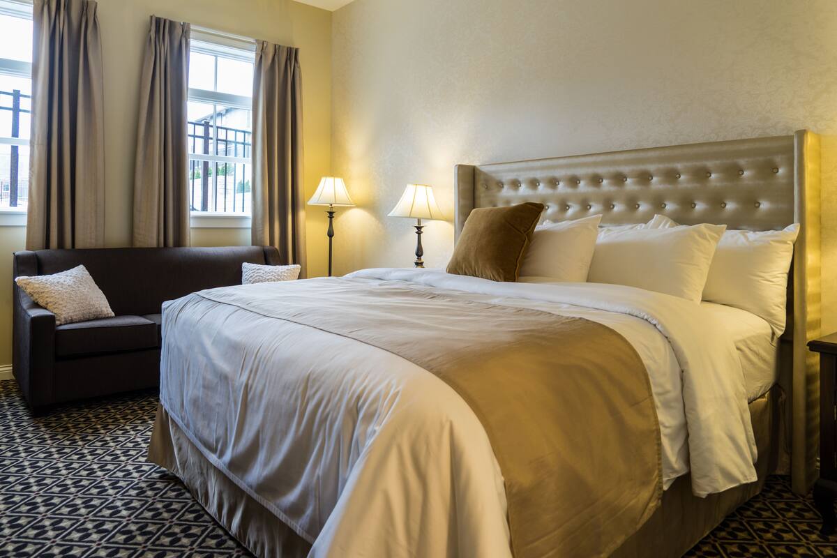 Une chambre d’hôtel avec un grand lit, un canapé, deux lampes et un sol à motifs.