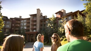A multi-story building with a stone facade and multiple balconies, surrounded by trees. - Panorama Mountain Resort - Premium Condos and Townhomes (Panorama)