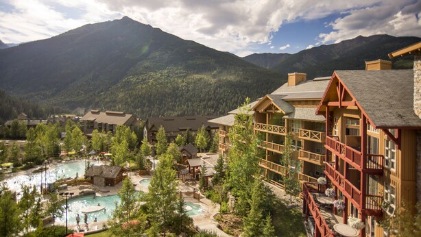 A resort with multiple buildings, a pool area, and a mountainous backdrop. - Panorama Mountain Resort - Premium Condos and Townhomes (Panorama)