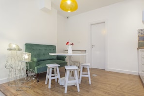Um quarto com um sofá verde, uma mesa redonda branca e um suporte decorativo de arame.