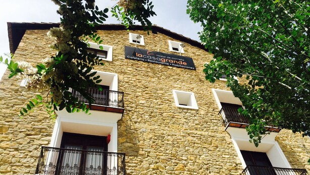 Ein Gebäude aus Stein mit Balkonen und einem Schild, das es als Hostel, Café, Restaurant und Unterkunft kennzeichnet.