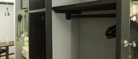 A corner of a room with a dark door, a small shelf, and a tiled floor.