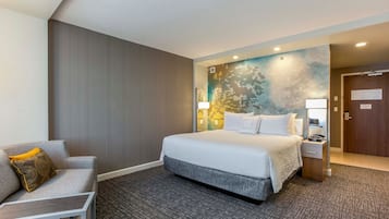 A hotel room with a bed, a desk, a chair, and a nightstand.