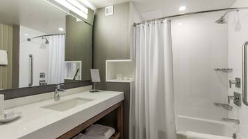A modern bathroom with a double sink, a shower, and a vanity with a mirror.