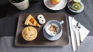 Una bandeja con una galleta, una porción de tarta, un tazón de cereal, una manzana y un plato con rodajas de kiwi.