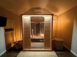 A room with a sliding door, a ceiling fan, a wall-mounted air conditioner, a basket, and a floor lamp.