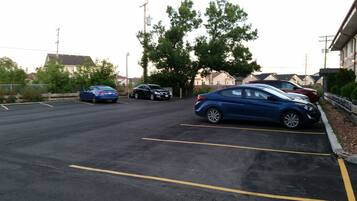 Un parking où sont garées plusieurs voitures, dont une berline bleue et une berline noire.