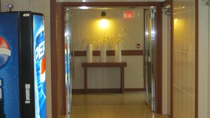 Una hall d'albergo con un frigorifero Pepsi, una reception e un segnale di uscita montato a parete.