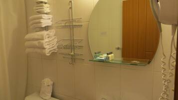 Un baño con inodoro, lavamanos, toallero y espejo.