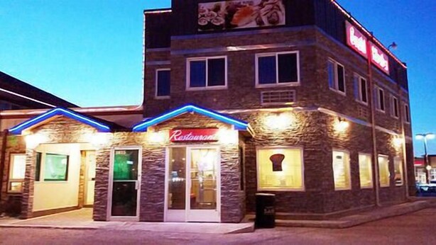 Un ristorante con facciata in pietra e insegna al neon.