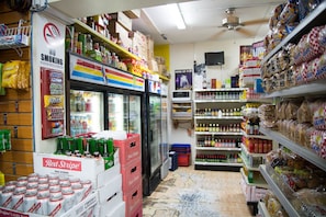 Uma loja de conveniência com prateleiras repletas de lanches, bebidas e produtos embalados.