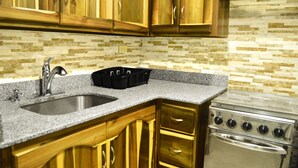 A kitchen with granite countertops, wooden cabinets, a stainless steel sink, and a built-in oven. - Paradise Beach Studio At Montego Bay Club (Montego Bay)