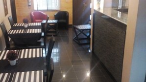 A dining area with striped tablecloths, black chairs, and a small potted plant. - Swisscottage suites (Lagos)