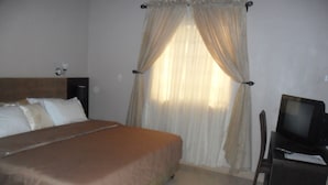 A hotel room with a bed, a television, and curtains. - Swisscottage suites (Lagos)
