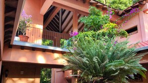 A multi-level building with balconies, potted plants, and a central fern plant. - La Villa de Soledad B&B (La Ceiba)
