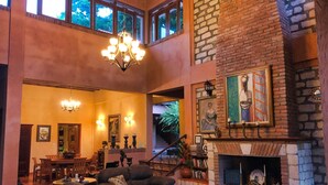 A spacious living room with a fireplace, a chandelier, and a dining area. - La Villa de Soledad B&B (La Ceiba)