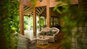 A covered outdoor seating area with wicker furniture and a wooden ceiling. - La Villa de Soledad B&B (La Ceiba)