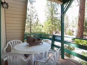 Relax in this serene outdoor seating area with a round table and four chairs, surrounded by lush greenery and a distant view.